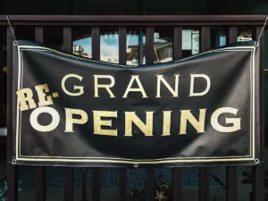A black PVC banner with eyelets, printed in gold and white, tied to railings